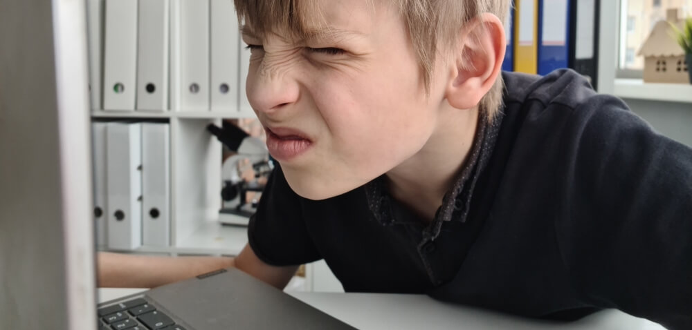Dječak škilji u ekran kao simptom astigmatizma 